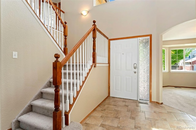 11335 W 54th Ln, Arvada, CO 80002 - entrance foyer with light stone finish flooring, arched walkways, baseboards, stairway, and a towering ceiling