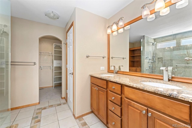 11335 W 54th Ln, Arvada, CO 80002 - full bath with a spacious closet, double vanity, tile patterned flooring, tiled shower, and baseboards
