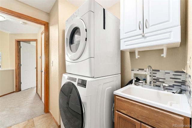 11335 W 54th Ln, Arvada, CO 80002 - laundry room featuring stacked washer and clothes dryer, cabinet space, and light carpet