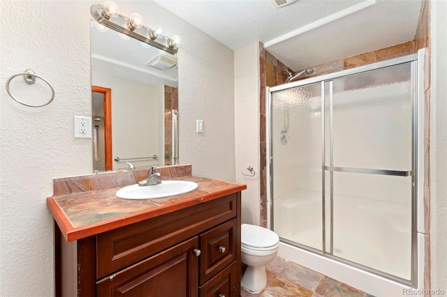 11335 W 54th Ln, Arvada, CO 80002 - bathroom with a textured wall, toilet, a stall shower, vanity, and stone finish floors