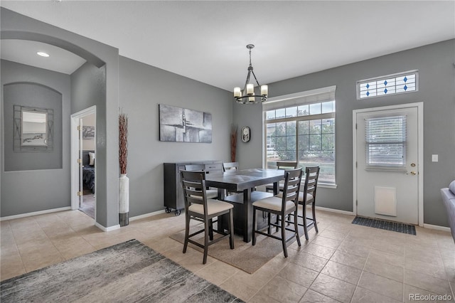 dining area with arched walkways, baseboards, a notable chandelier, and light tile patterned floors
