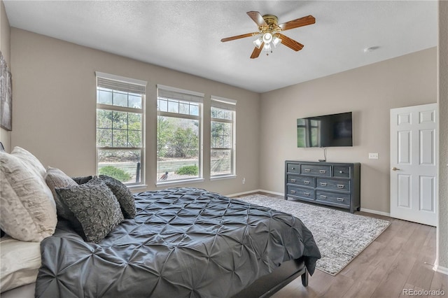 bedroom featuring wood finished floors, baseboards, and ceiling fan