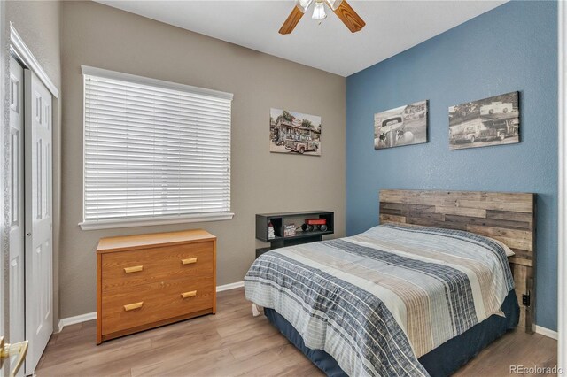 bedroom with light wood-style flooring, a closet, a ceiling fan, and baseboards