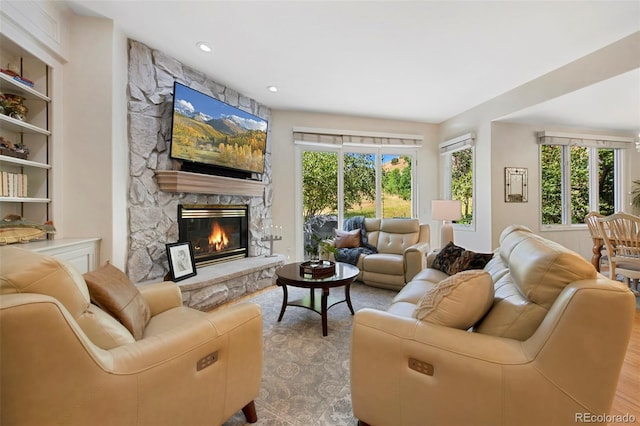 living room featuring built in shelves, a fireplace, and a healthy amount of sunlight