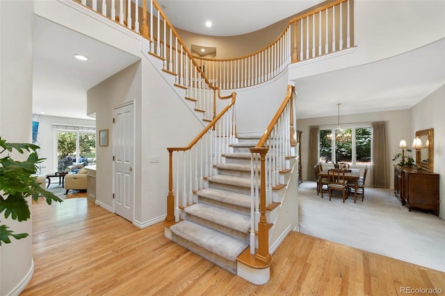 stairway with hardwood / wood-style floors, a high ceiling, and a wealth of natural light