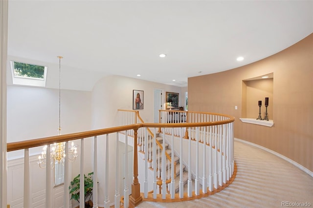 hall with an inviting chandelier, carpet flooring, and a skylight