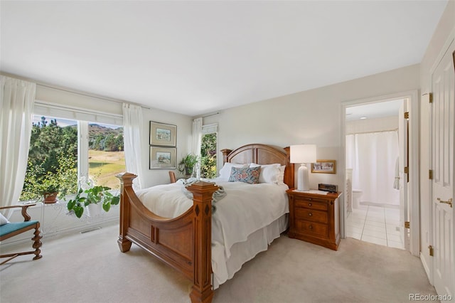 bedroom with ensuite bath and light carpet