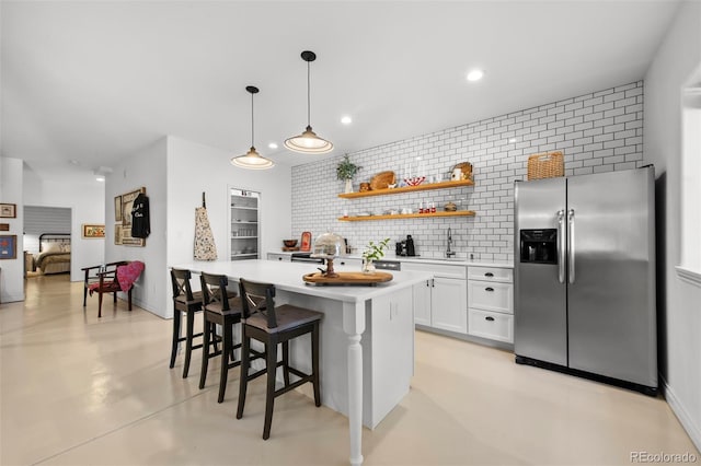 kitchen featuring white cabinetry, hanging light fixtures, tasteful backsplash, a kitchen bar, and stainless steel fridge with ice dispenser