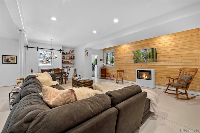 living room with a barn door, a notable chandelier, and wooden walls