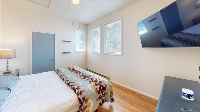 bedroom with a baseboard heating unit, ceiling fan, and hardwood / wood-style floors