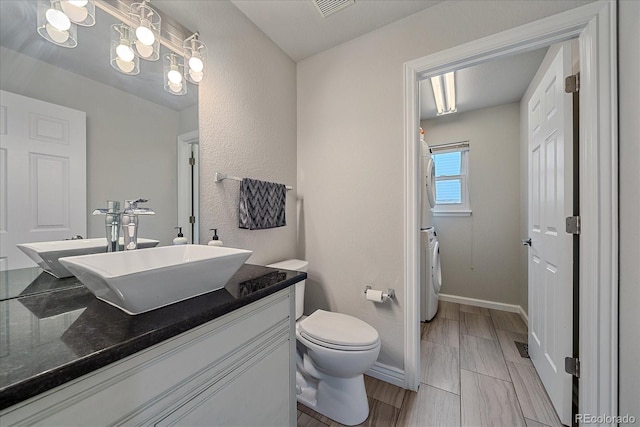 bathroom with vanity, toilet, washer / dryer, and a notable chandelier