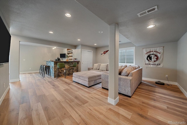 living room with a textured ceiling and light hardwood / wood-style flooring