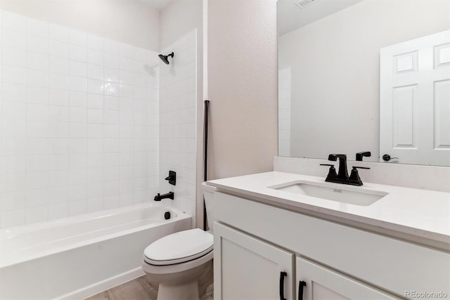 full bathroom featuring vanity, hardwood / wood-style floors, tiled shower / bath, and toilet