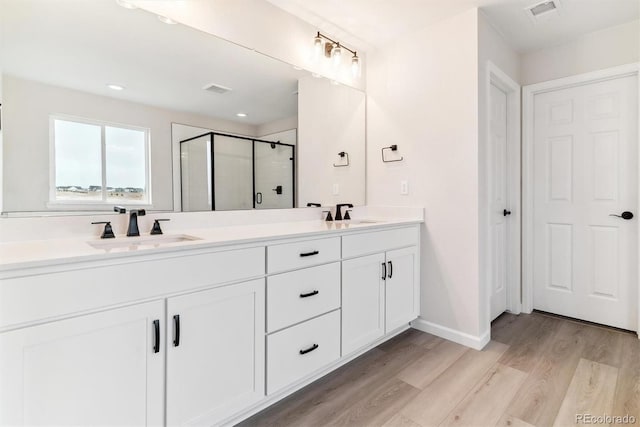 bathroom with a shower with door, vanity, and wood-type flooring