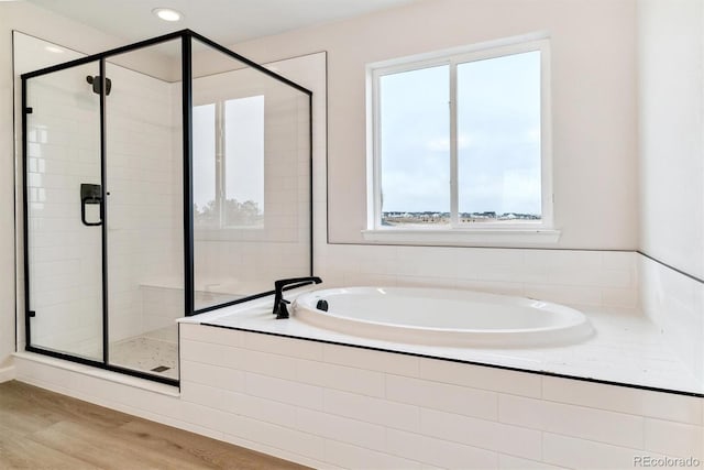 bathroom featuring plus walk in shower and hardwood / wood-style floors