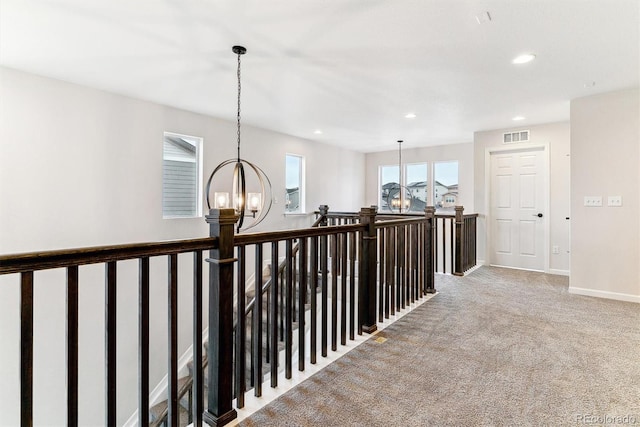 hall featuring carpet flooring and an inviting chandelier