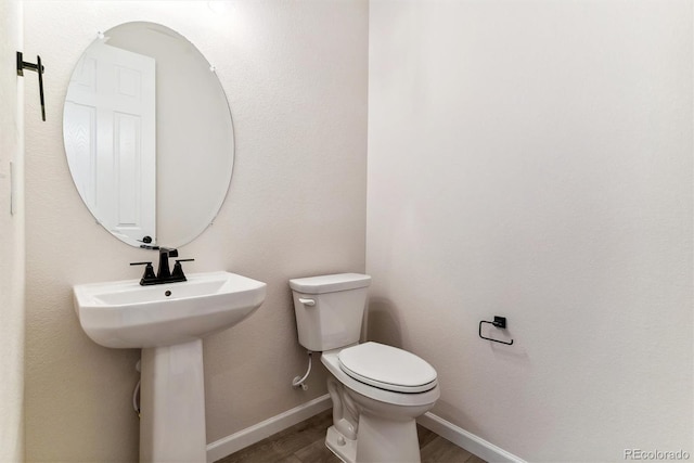 bathroom with toilet, wood-type flooring, and sink