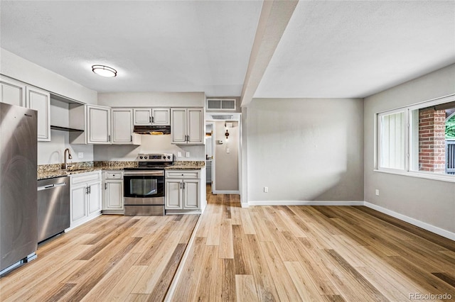 3663 S Sheridan Blvd Unit L6, Denver, CO 80235 - kitchen with appliances with stainless steel finishes, exhaust hood, light wood-type flooring, stone counters, and a textured ceiling