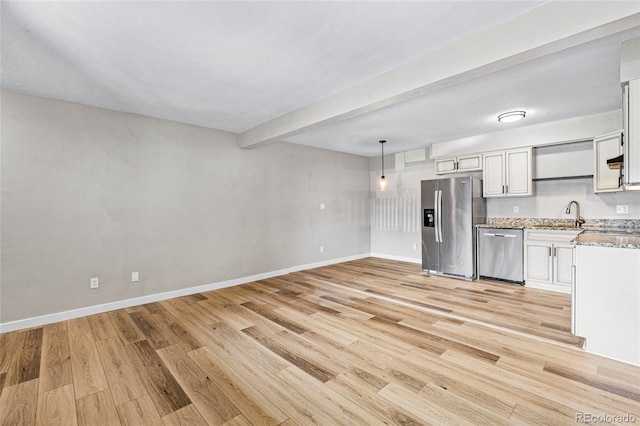 3663 S Sheridan Blvd Unit L6, Denver, CO 80235 - kitchen with appliances with stainless steel finishes, light wood-style floors, beamed ceiling, light stone counters, and decorative light fixtures