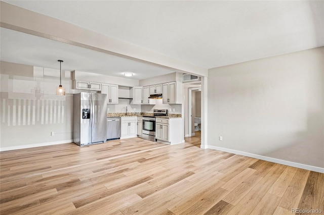 3663 S Sheridan Blvd Unit L6, Denver, CO 80235 - kitchen with appliances with stainless steel finishes, under cabinet range hood, light wood-type flooring, light countertops, and pendant lighting