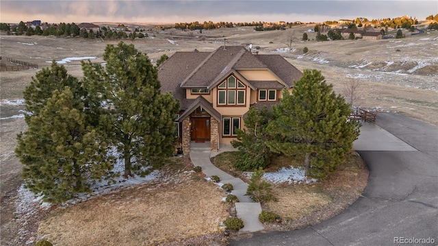 view of front of property featuring concrete driveway, stone siding, and stucco siding