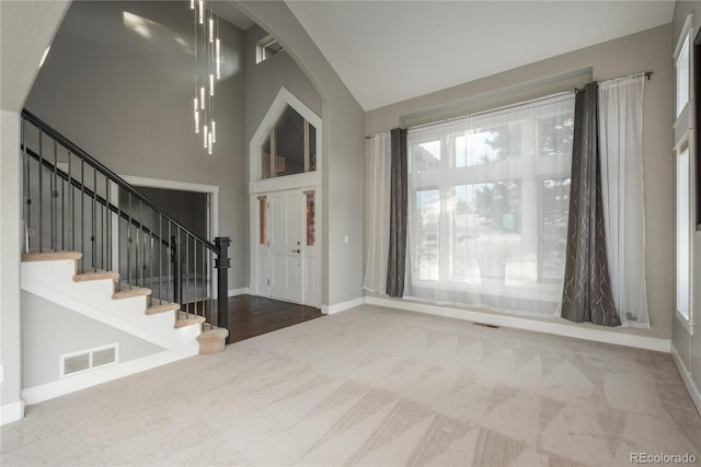 carpeted entryway featuring visible vents, plenty of natural light, and high vaulted ceiling