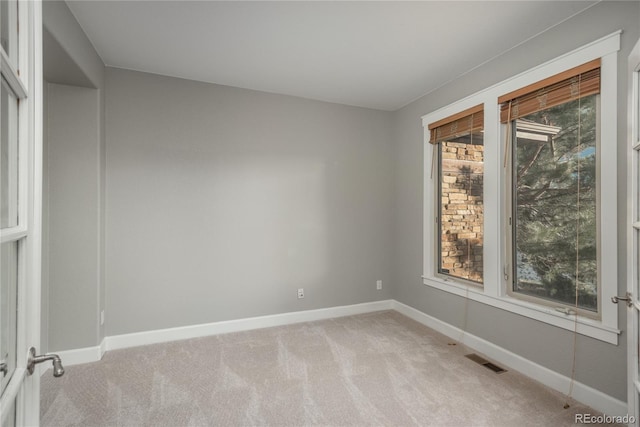 spare room with visible vents, light colored carpet, and baseboards