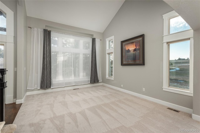 carpeted empty room with visible vents, high vaulted ceiling, and baseboards