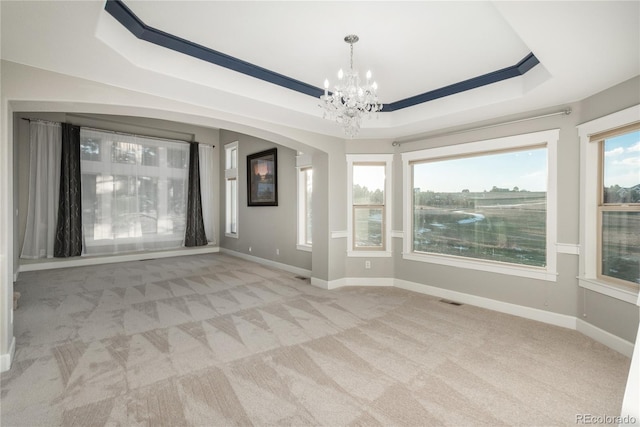 carpeted empty room featuring a chandelier, visible vents, a raised ceiling, and baseboards