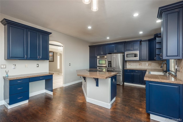 kitchen with tasteful backsplash, blue cabinetry, arched walkways, stainless steel appliances, and a sink