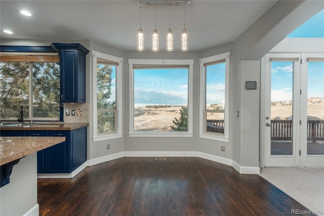 unfurnished dining area with a wealth of natural light, baseboards, and dark wood-style flooring
