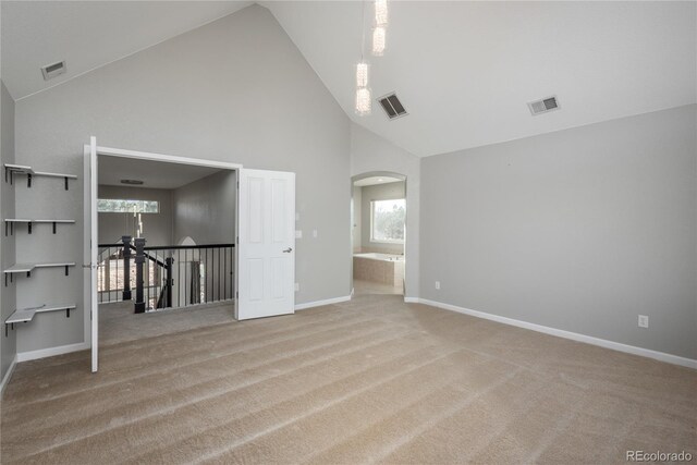 spare room featuring visible vents, arched walkways, carpet, and baseboards