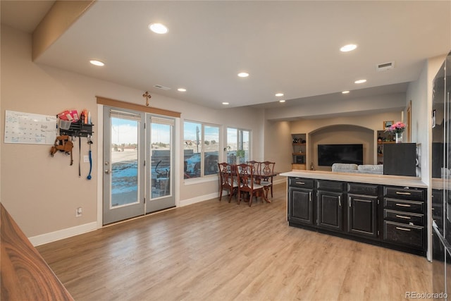 kitchen with open floor plan, visible vents, dark cabinets, and light wood finished floors