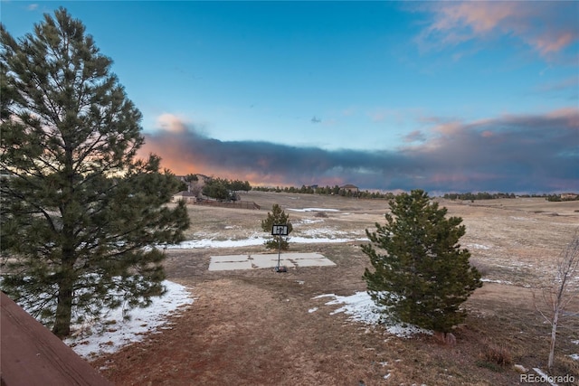 yard at dusk featuring a rural view