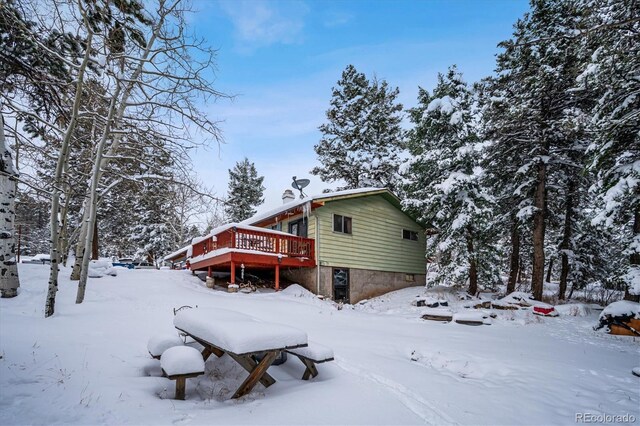 snow covered house with a wooden deck