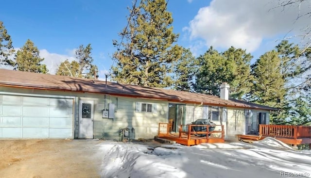 rear view of property featuring a wooden deck and a garage