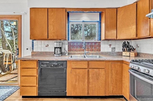 kitchen with black dishwasher, stainless steel gas range oven, wood finished floors, a sink, and backsplash