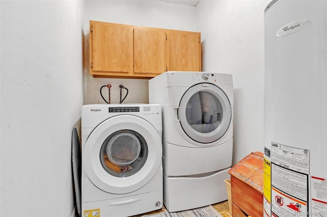 washroom featuring water heater, cabinet space, and washer and clothes dryer