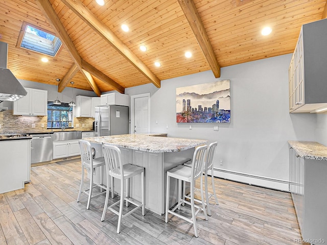 kitchen featuring lofted ceiling with skylight, appliances with stainless steel finishes, hanging light fixtures, and light wood-type flooring