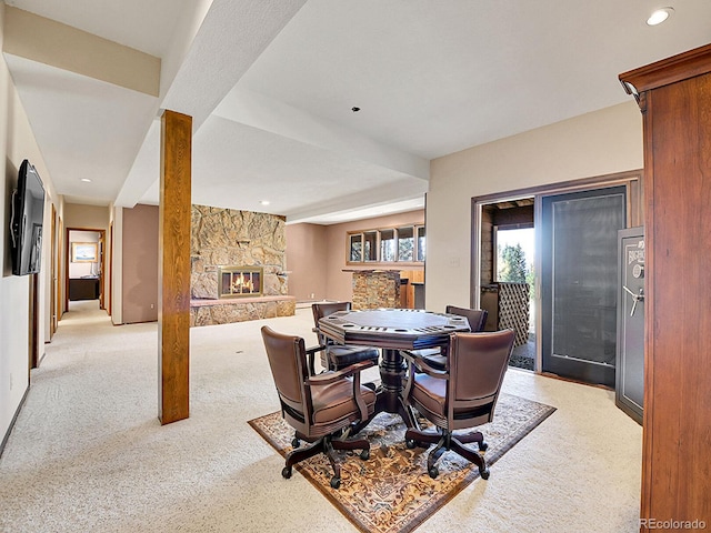 carpeted dining space featuring a stone fireplace