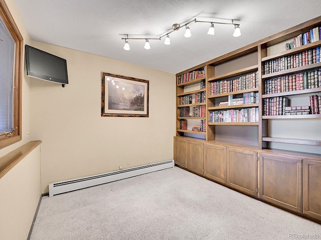 empty room with a textured ceiling, track lighting, and baseboard heating