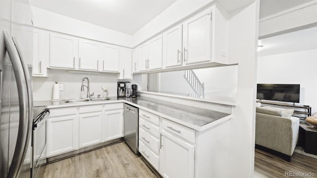 677 Vrain St Unit 15, Denver, CO 80204 - kitchen featuring stainless steel appliances, a sink, open floor plan, light wood-style flooring, and white cabinetry