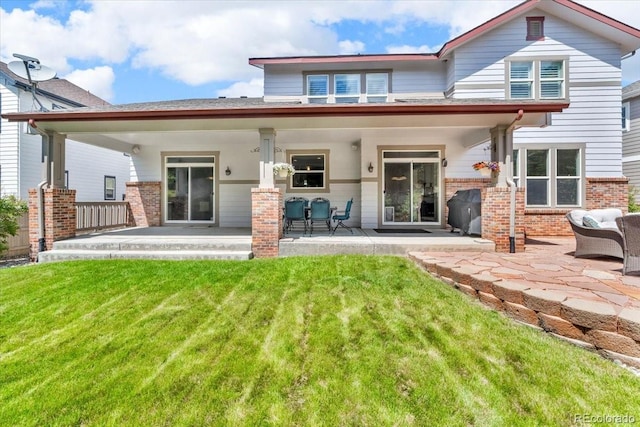 10683 Amesbury Way, Highlands Ranch, CO 80126 - rear view of house with brick siding, a lawn, and a patio area