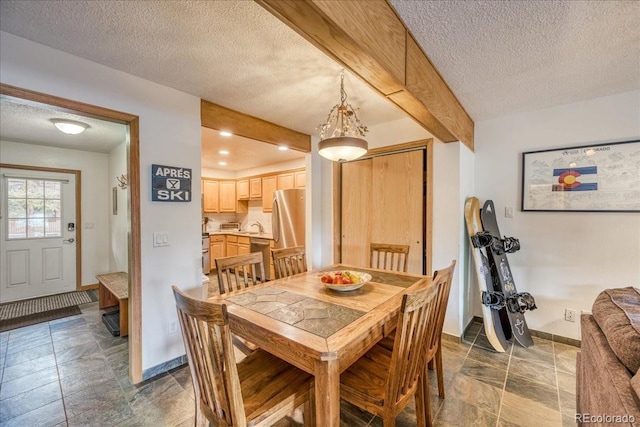 23004 US Highway 6 Unit 103, Dillon, CO 80435 - dining space featuring a textured ceiling, dark stone finish floors, and beam ceiling