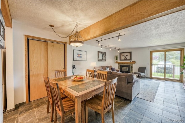 23004 US Highway 6 Unit 103, Dillon, CO 80435 - dining room featuring a textured ceiling, a glass covered fireplace, and rail lighting