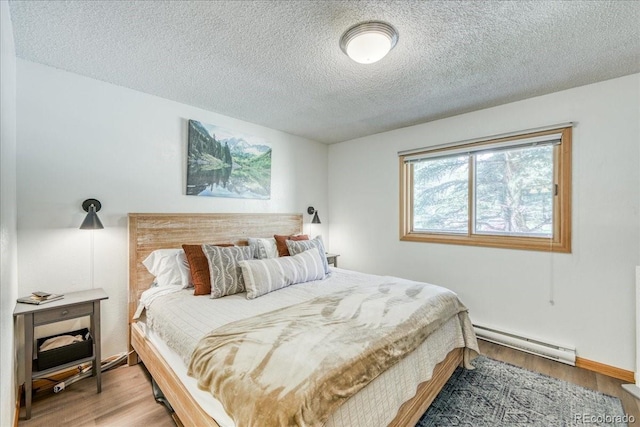 23004 US Highway 6 Unit 103, Dillon, CO 80435 - bedroom featuring baseboard heating, a textured ceiling, and wood finished floors
