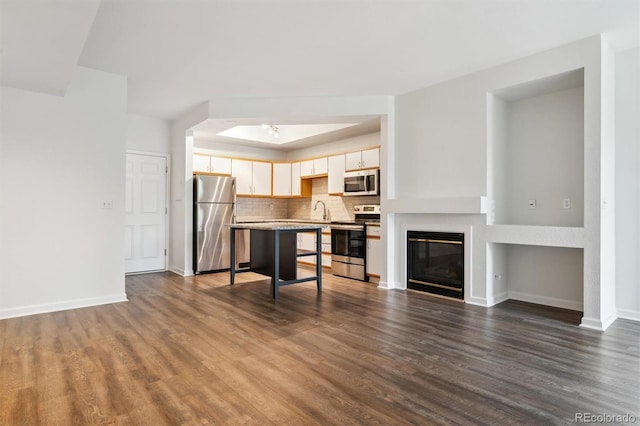 2824 W Centennial Dr Unit L, Littleton, CO 80123 - unfurnished living room with dark wood finished floors, baseboards, a tray ceiling, and a glass covered fireplace