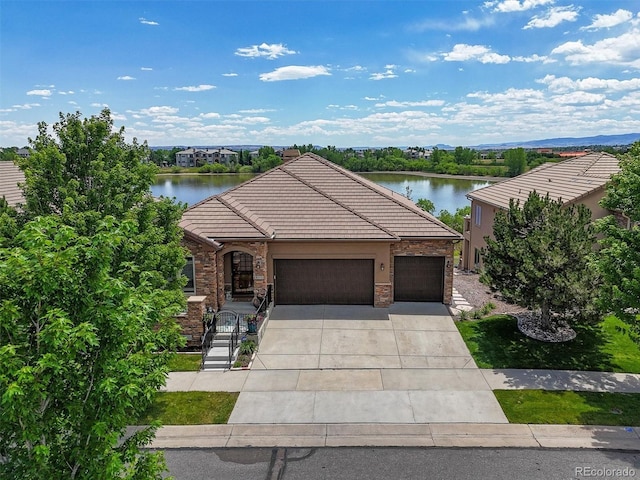 8070 W Progress Cir, Littleton, CO 80123 - view of front of home with a garage, driveway, stone siding, a tile roof, and a water view