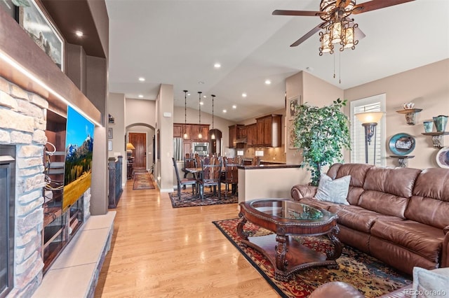 8070 W Progress Cir, Littleton, CO 80123 - living area with ceiling fan, lofted ceiling, a fireplace, arched walkways, and light wood-style floors