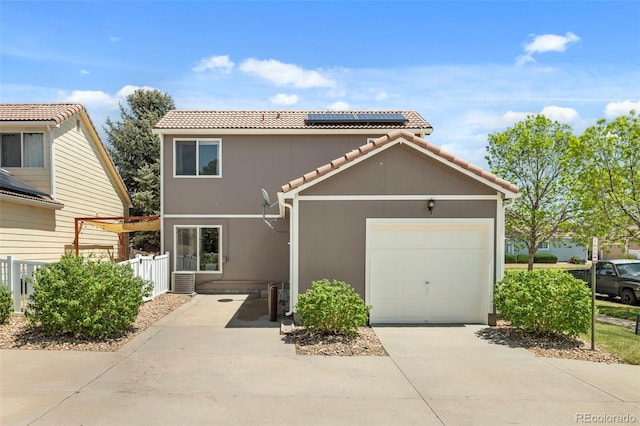 4713 Perth St, Denver, CO 80249 - view of front of house featuring solar panels, concrete driveway, a tile roof, an attached garage, and fence